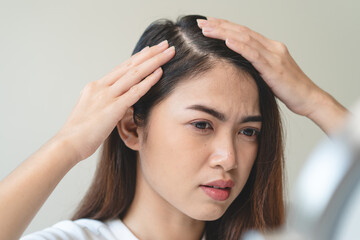 Fototapeta premium Hair loss problem, Asian woman look at scalp worry about balding.