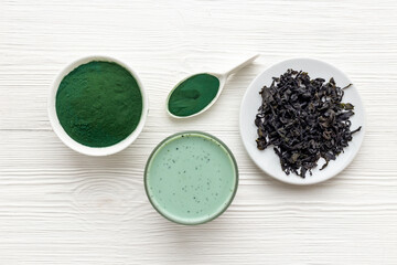 Spirulina algae powder in bowl and cold milk latte drink, top view