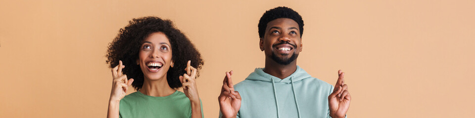 Black man and woman expressing happiness with fingers crossed