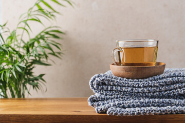 Сup of hot tea and blue knitted plaid on wooden bench. Close-up view of home comfort