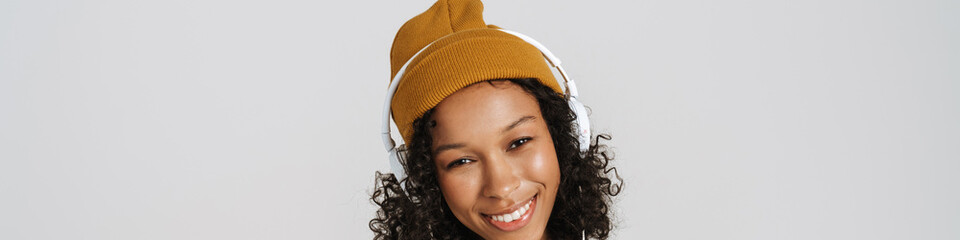 Black woman wearing hat smiling while listening music with headphones