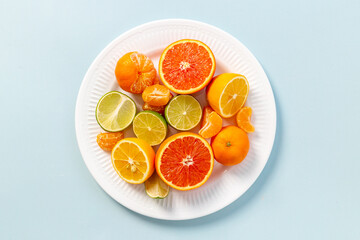 White plate full of fresh citrus fruits, top view