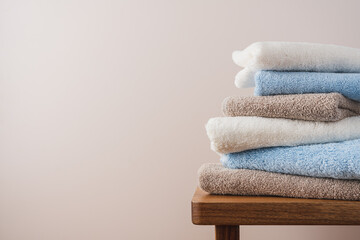 Stack of blue white beige cotton terry towels close up view. Bathroom interior details with copy space - obrazy, fototapety, plakaty