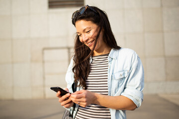 Pretty young asian woman looking at cell phone standing in the city