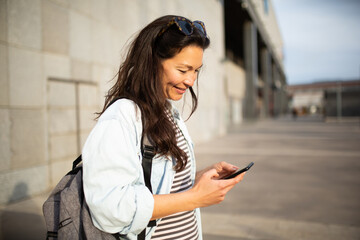 Smiling young asian woman using mobile phone standing in the city