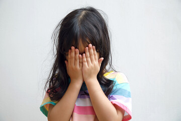 Child covering face with hands; Shy girl hiding her face