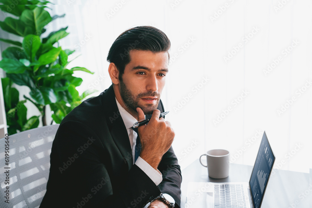 Poster modern professional businessman at modern office desk using laptop to work and write notes. diligent