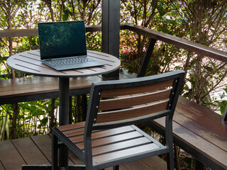 laptop sits on the wooden table on the balcony, creating a harmonious blend of technology and...