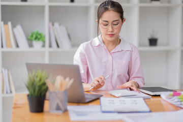  Asian business woman wear glasses or accountant working on calculator to calculate business data, accounting document and laptop computer at office, business concept