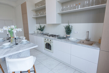 close view kitchen with dinning marble table and hight bar stools in minimalistic light elegant luxury design of a modern spacious studio apartment in soft pastel beige colors