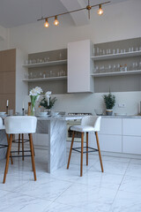 close view kitchen with dinning marble table and hight bar stools in minimalistic light elegant luxury design of a modern spacious studio apartment in soft pastel beige colors