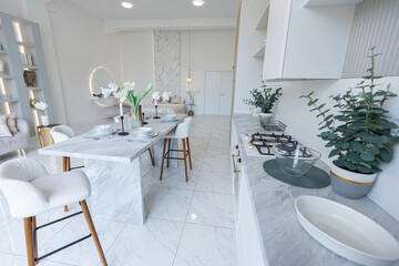 minimalistic light elegant luxury design of a modern spacious studio apartment with kitchen area, bedroom and huge mirror behind the couch. tiles on the floor and high ceiling.
