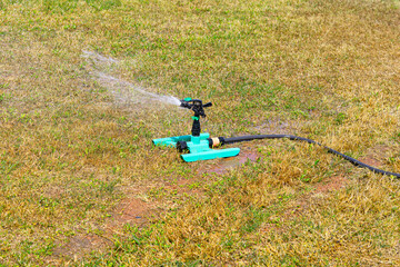 Sprinkler spraying water on the green grass in the park 