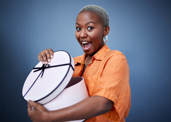 African woman, open present or box in studio portrait with excited smile, surprise and blue...