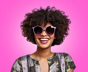 A woman with an afro hairstyle smiling and wearing sunglasses over pink background