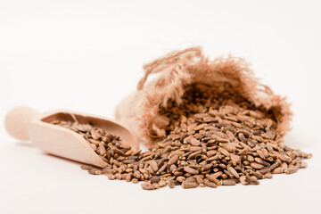 raffia cloth bag with a wooden spoon with milk thistle seeds or Silybum marianum healing medicinal plant for liver isolated on white background