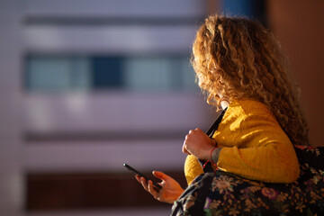 Young woman walking with bag and mobile phone outside in the city