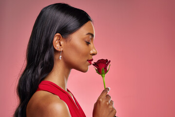 Face, woman and smelling a rose on a studio background for valentines day. Fragrance, model and...