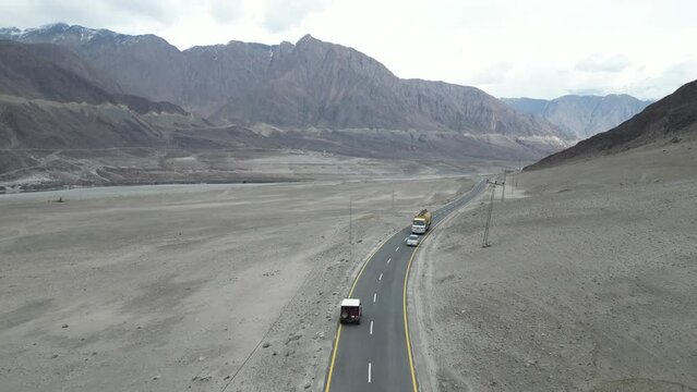 Scenic landscape view of Karakoram Highway with huge rocky mountains in background near Chilas, Gilgit Baltistan North of Pakistan. Oil tanker and few vehicles cross jeep from other side on highway.