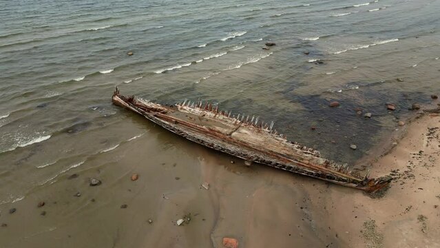 Abandoned shipwreck, An abandoned broken boat full of holes lying on the seashore. Wreck ship on reefs in sea or ocean. The sunken ship, the ship ran aground. Ecological disaster of the Aral Sea.