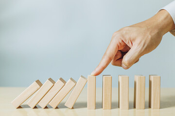 A person use finger stopping wood pieces of a domino effect. Concept of risk management, risk...