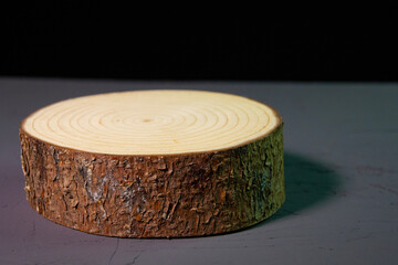 Beautiful wooden stand on a black background. Wooden decor on a concrete surface. Decorative log with bark.