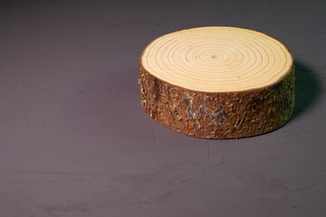 Beautiful wooden stand on a dark background. Wooden decor on a gray concrete surface. Decorative log with bark.