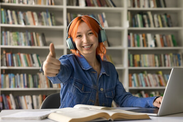 Happy fresh college student girl in headphones recommending education, enjoying studying in campus...