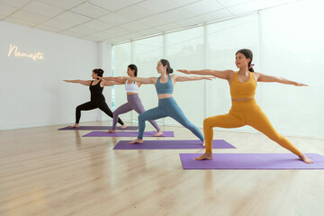 Fototapeta na wymiar A group of women in yoga class doing the warrior pose