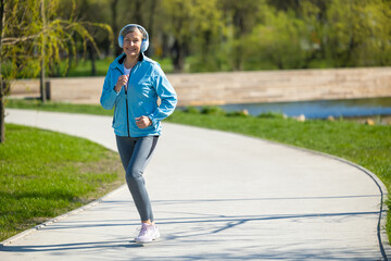 Smiling woman in blue blazer running in the park