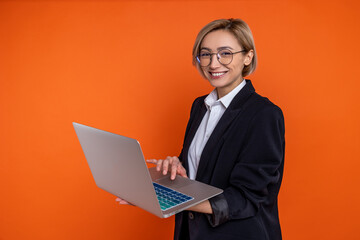 Confident businesswoman wearing black official style suit working on laptop in office