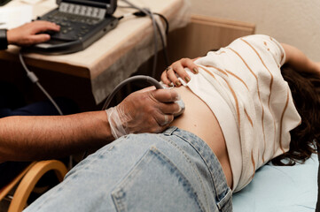 Fototapeta premium ultrasound of the kidneys and abdomen in a young woman. close-up of the hand of an uzist checking the kidneys of a patient. medical examination on ultrasound.