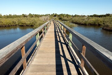 Wooden boardwalk trail through a marsh preserve in Flagler Beach, Florida on a sunny day