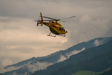 Fototapeta na wymiar a emergency help with a helicopter in the mountains at a cloudy summer day