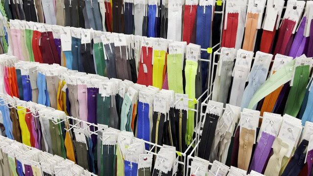 Many different zippers for clothes of different sizes and colors, zippers on racks in the workshop
