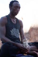Photographs of a young black gay man practicing Reiki in the desert.  - 619525263