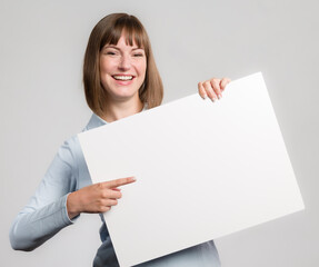 Young happy woman is pointing to an empty advertising board ready for lettering