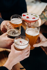 Friends hands toasting and having fun together drinking beer and cocktails at happy hour in pub restaurant . Social life style party time concept - 619529215