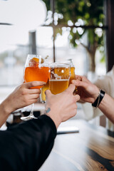 Friends hands toasting and having fun together drinking beer and cocktails at happy hour in pub restaurant . Social life style party time concept