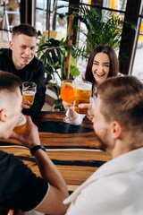 Happy group of friends drinking and clinking with beer and cocktails at brewery bar restaurant. Beverage life style concept with guys and girls having fun together