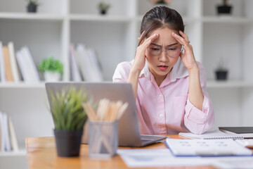 Obraz premium Portrait of tired young business Asian woman wear glasses work with documents tax laptop computer in office. Sad, unhappy, Worried, Depression, or employee life stress concept