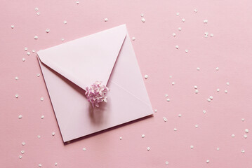 Blank greeting card mockup. Beige empty sheet of paper mockup in an pink envelope on pink paper background. flat lay. Wedding, business, birthday still life scene. Flower petals and lilac branch.