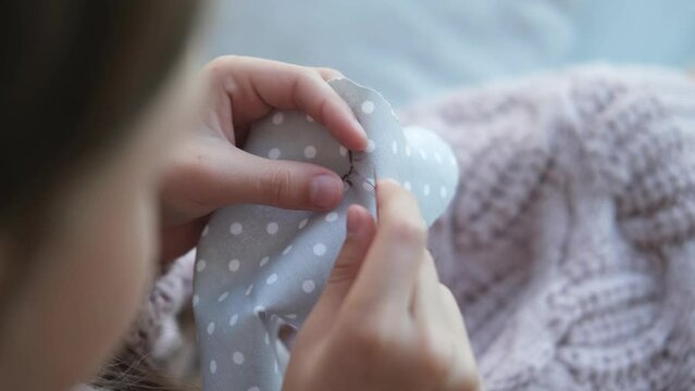 Close-up of a child's hands sewing a soft toy. The girl sews up a soft toy of an elephant. Handmade, hobby.