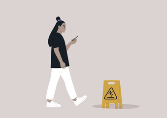 Fototapeta premium Young Asian character distracted by their smartphone ignoring a yellow wet floor caution sign on their way