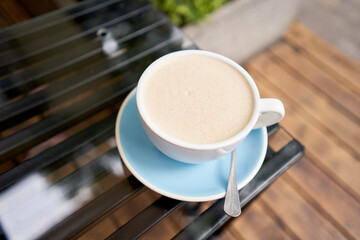 Cup of hot Peanut latte. The table in the coworking space of the coffee shop. A cup of coffee on the veranda on a sunny day. Coffee break at the cafe. Close-up