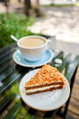 Cup of hot Peanut latte and Carrot pie. The table in the coworking space of the coffee shop. A cup of coffee on the veranda on a sunny day. Coffee break at the cafe. Close-up
