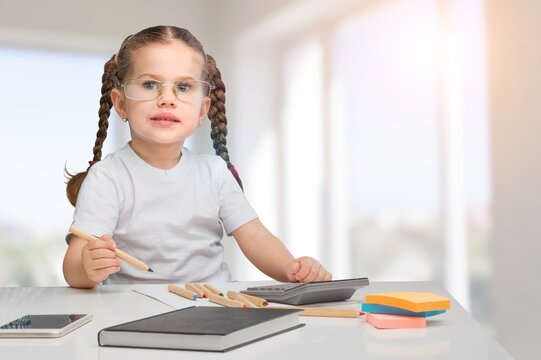 Cute small girl draws at a desk at home