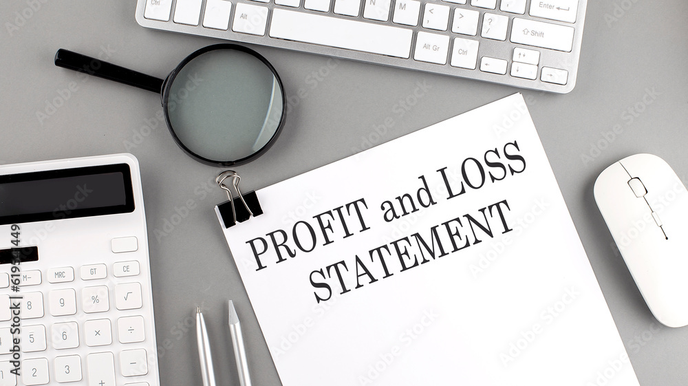 Poster profit and loss statement written on paper with office tools and keyboard on the grey background