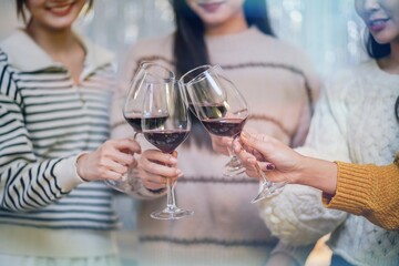 Cheerful friends enjoying home Birthday holiday party. Asian Friends cheering drinking red wine celebrating Christmas or New Year party