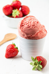 View of strawberry ice cream in white bowl on white table with strawberries, selective focus,...